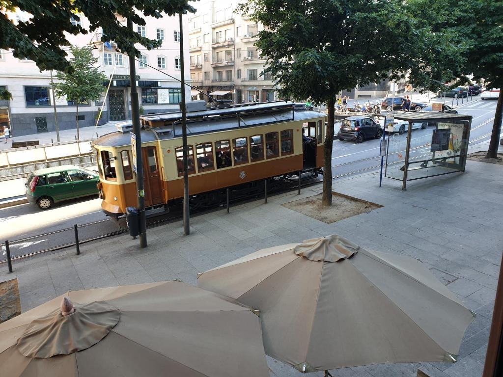 a yellow trolley car on a street with an umbrella at PORTO RICO STUDIOS in Porto