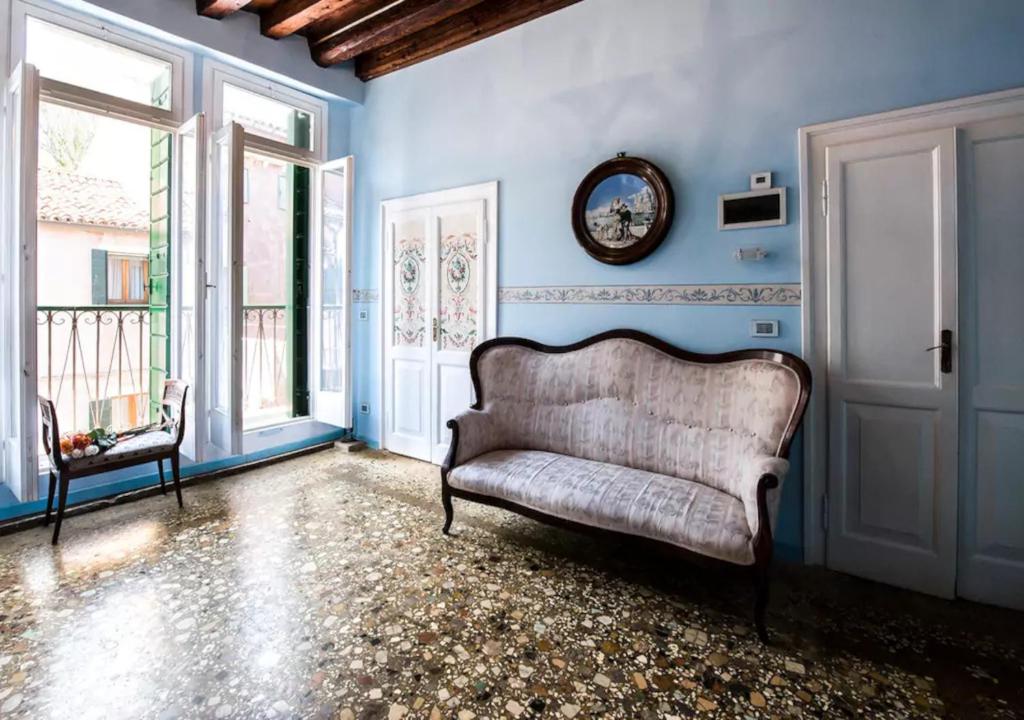 un sofá sentado en una habitación con paredes azules en Venice Giardini Biennale Apartment, en Venecia