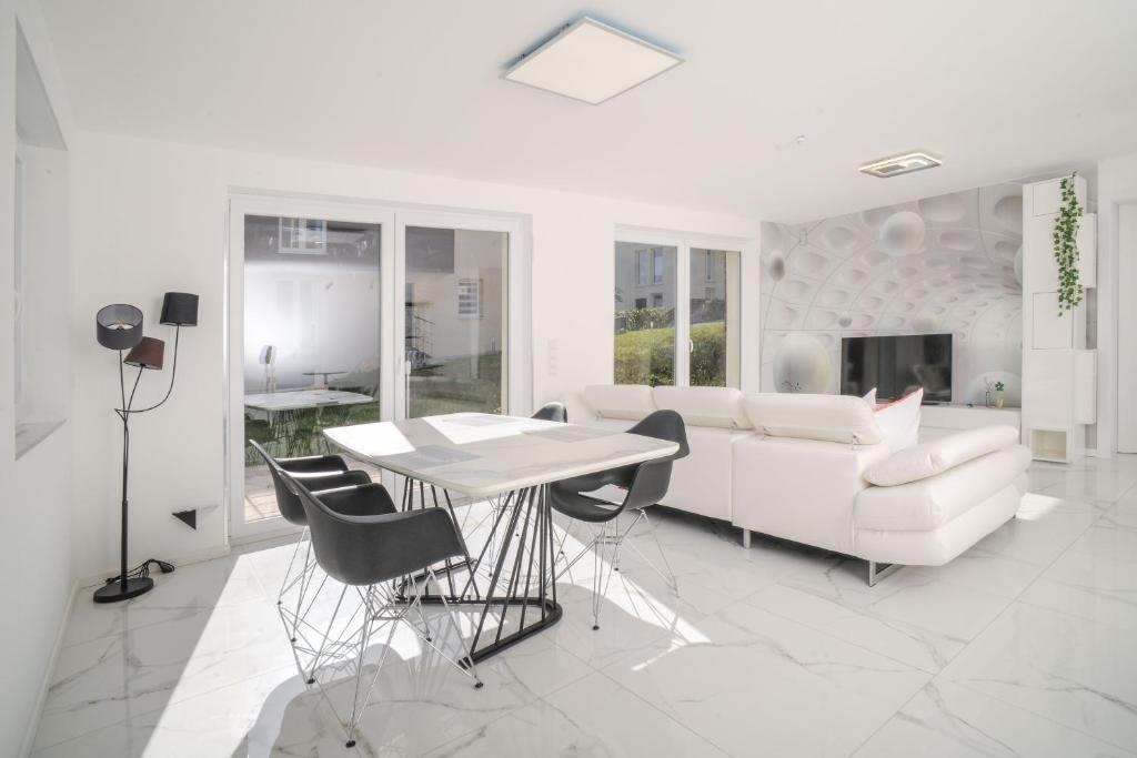 ein Wohnzimmer mit einem weißen Sofa, einem Tisch und Stühlen in der Unterkunft Designapartments Business and More - Sennhütte 9 in Wernigerode