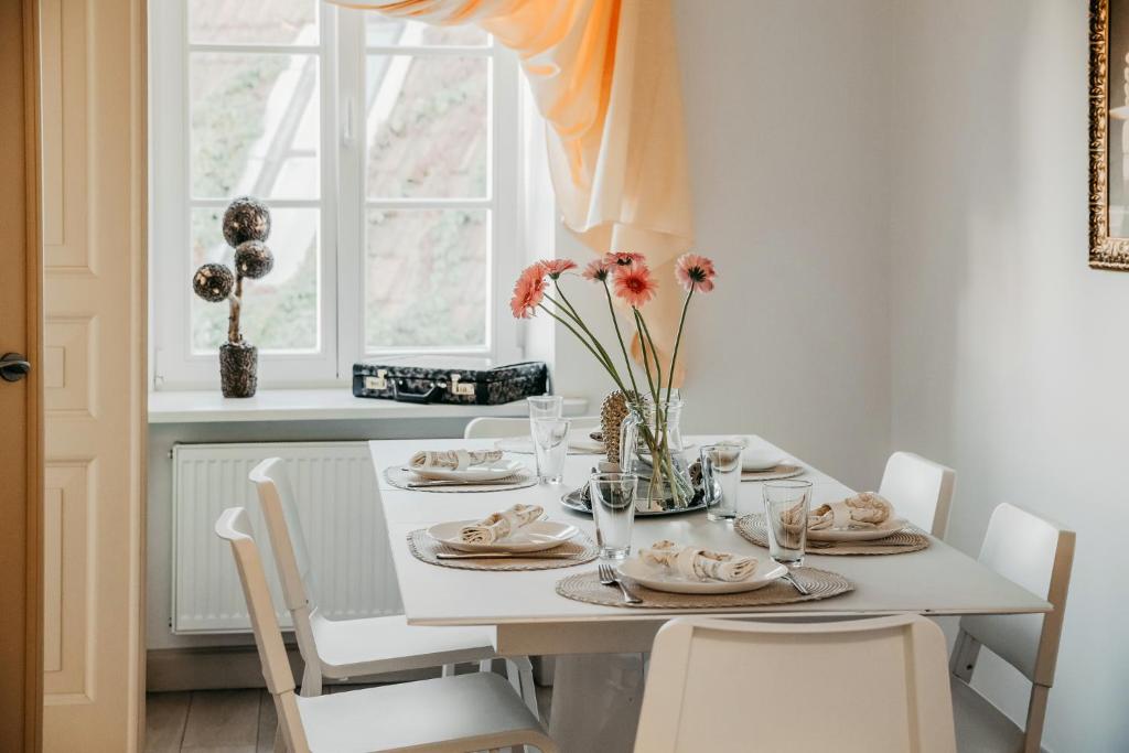una mesa de comedor blanca con un jarrón de flores en Spacious - 140 square meters Apartment, Vilnius City Centre, en Vilna