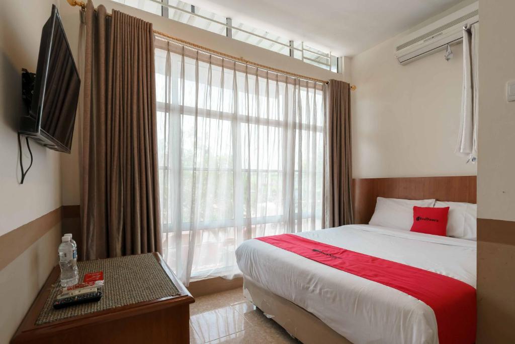 a bedroom with a bed and a large window at RedDoorz near Plaza Botania 1 Batam in Batam Center