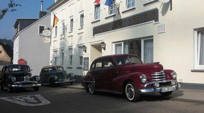 deux vieilles voitures garées devant un bâtiment dans l'établissement Hotel Stadt Coblenz, à Fachbach