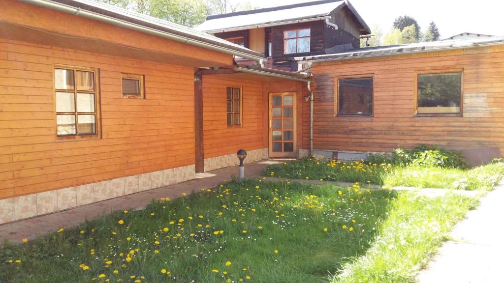 a house with a yard with yellow flowers in front of it at Apartment Svoboda nad upou 1 in Svoboda nad Úpou