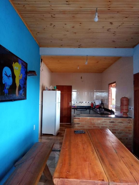 a kitchen with a wooden table and a refrigerator at hospedagem- Bela Vista in Milho Verde