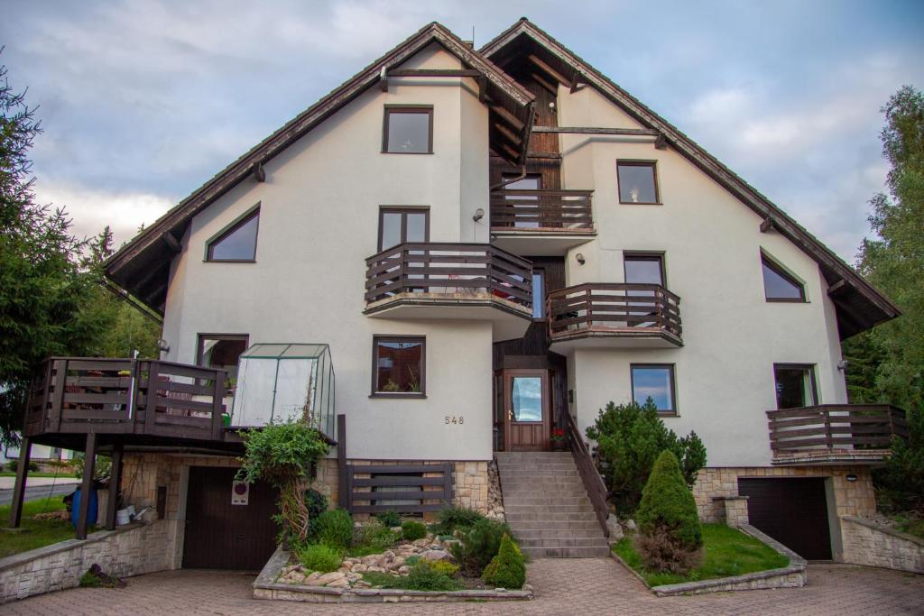 ein großes weißes Haus mit Balkon und Treppe in der Unterkunft Apartment Harrachov 3 in Harrachov