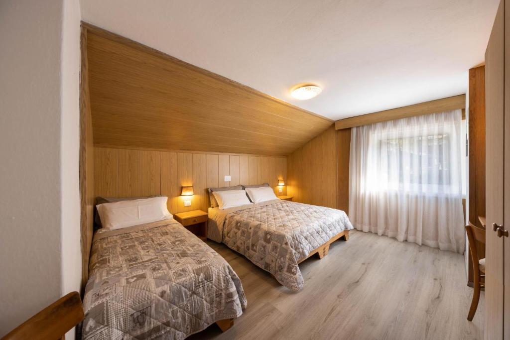 a hotel room with two beds and a window at Appartamento Primavera 3 in Moena