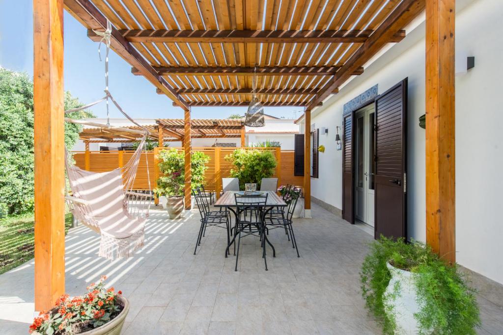 a patio with a table and chairs under a wooden pergola at Villa Cinzia-150 mt from the beach in Mondello
