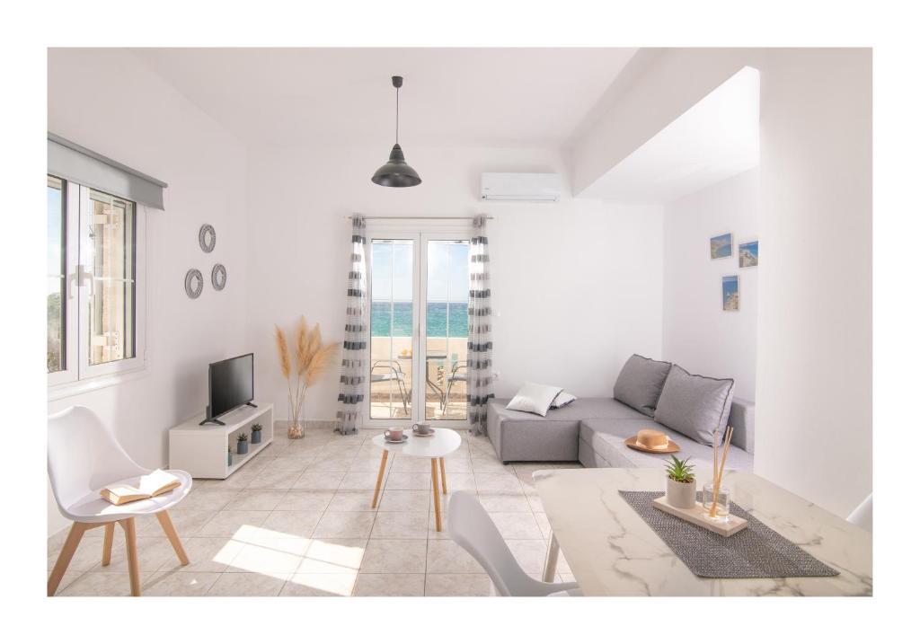a white living room with a couch and a tv at Kastri Mare Sea View Residences by Estia in Keratokampos