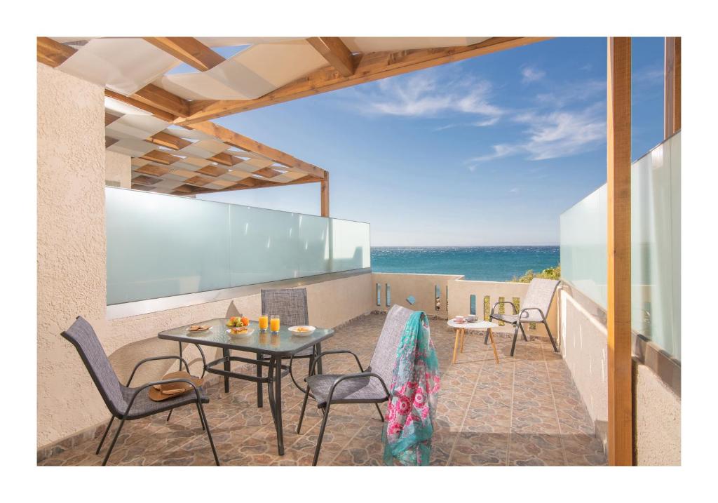 eine Terrasse mit einem Tisch, Stühlen und Meerblick in der Unterkunft Kastri Mare Sea View Residences by Estia in Keratókambos