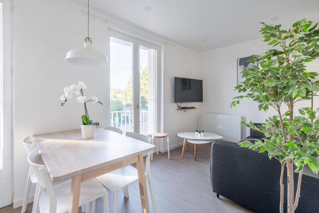 a white living room with a table and plants at Welcome perche ! Appartements 3 étoiles à NOGENT le Rotrou in Nogent-le-Rotrou