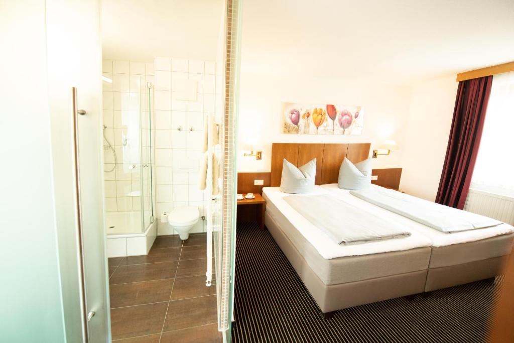 a bedroom with a bed and a bathroom with a shower at Stadthotel Giengen und Restaurant in Giengen an der Brenz