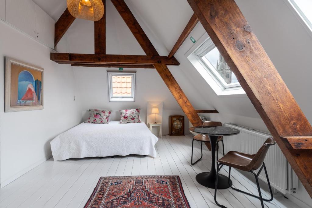 a bedroom with a bed and a table in a attic at The Blue House in Bruges