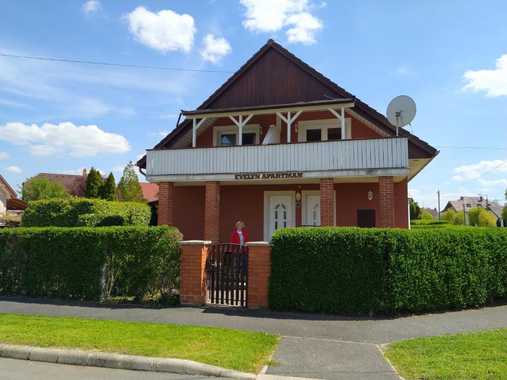 a woman standing in front of a house at Evelyn Apartman in Bük