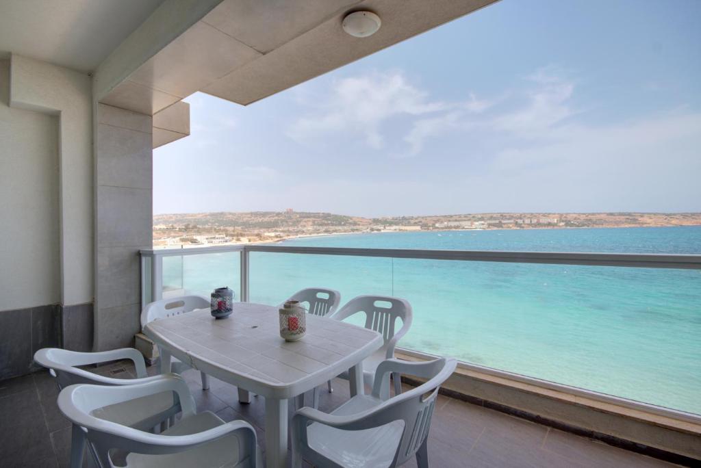 einen Tisch und Stühle auf einem Balkon mit Meerblick in der Unterkunft Enjoy Sunsets at Luxury 3BR APT in Mellieha Bay in Mellieħa
