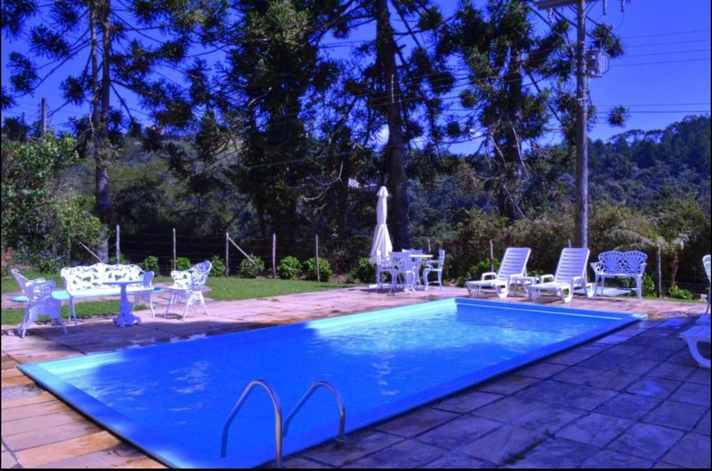 a swimming pool with chairs and a table next to it at Apto Econômico in Campos do Jordão