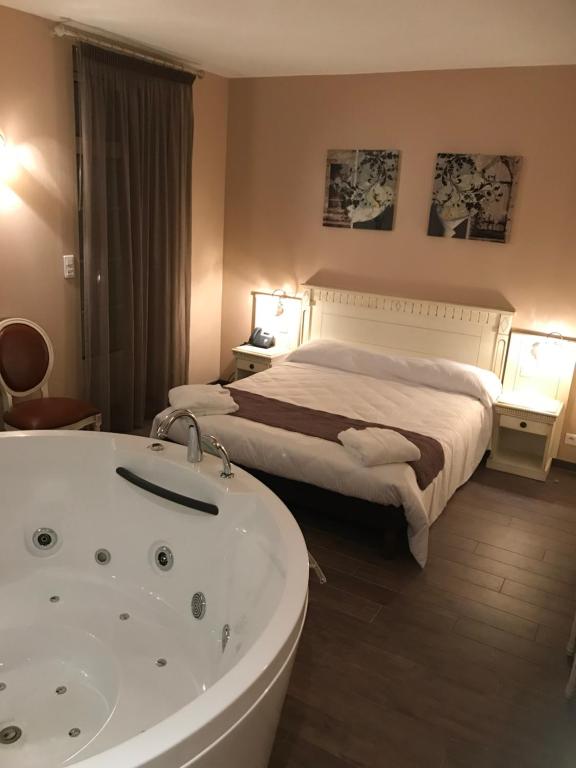 a hotel room with a tub and a bed at Logis Hôtel restaurant Les Minotiers in Mirepoix