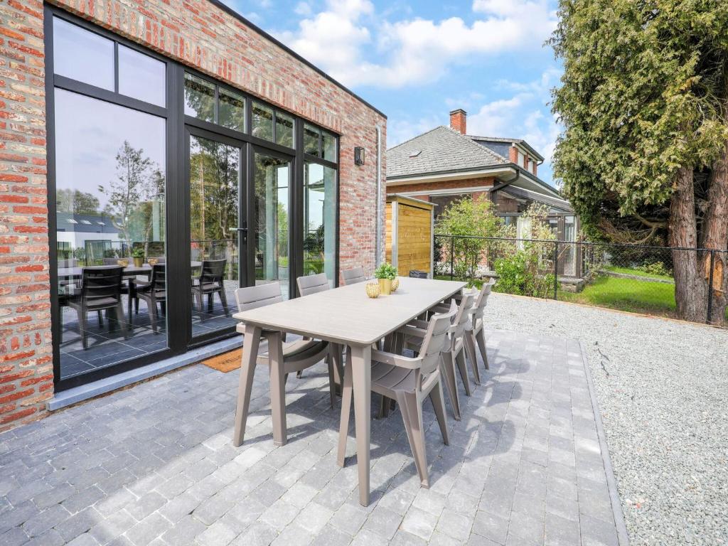 Beautiful house in Flemish Ardennes for cyclists في رونس: فناء مع طاولة وكراسي على مبنى من الطوب