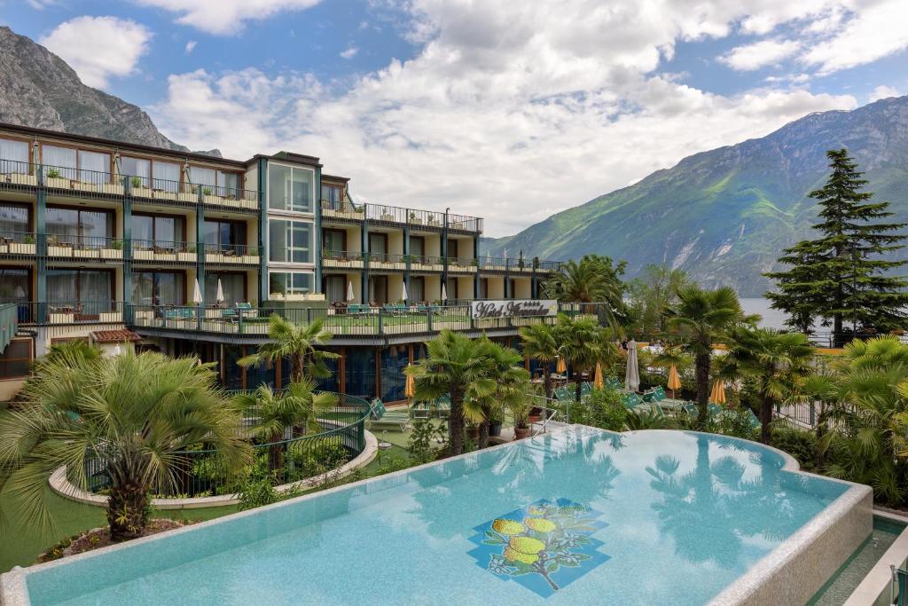 a resort with a pool and mountains in the background at Hotel Alexander in Limone sul Garda