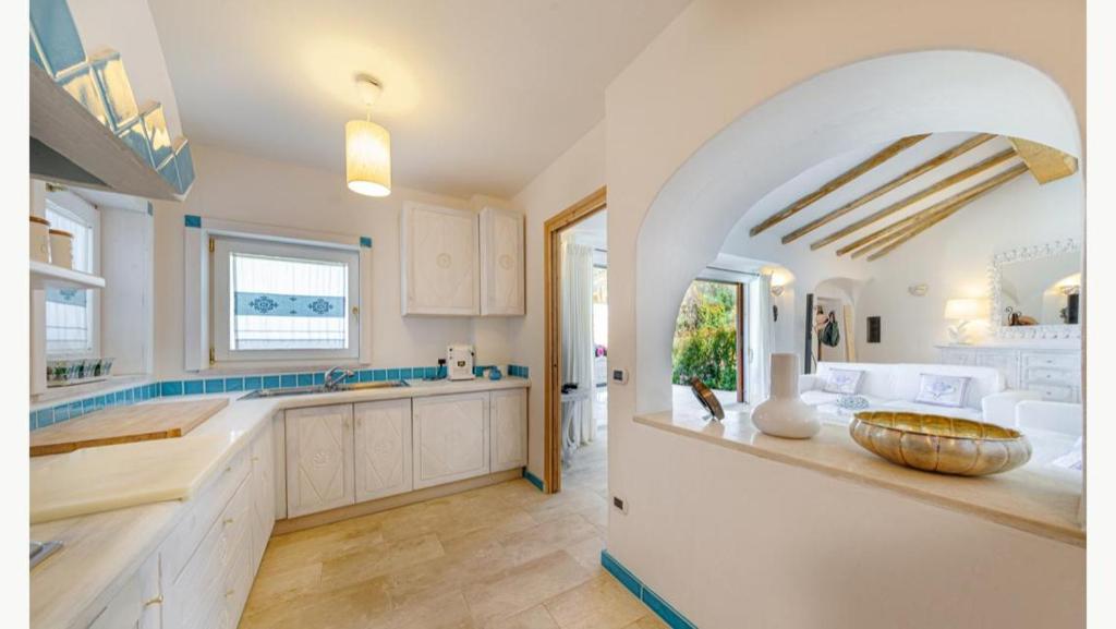 - une cuisine avec des placards blancs et un bol sur un comptoir dans l'établissement Sardinia Family Villas - Villa MariaPia with private pool and seaview, à Porto Cervo