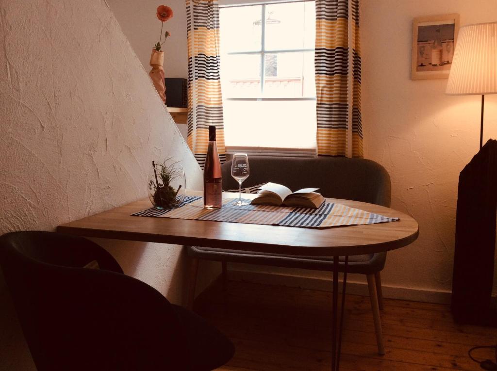 einen Tisch mit einem Buch und einem Glas Wein darauf in der Unterkunft Winzerhäuschen, Weingut Th. Müller in Reil