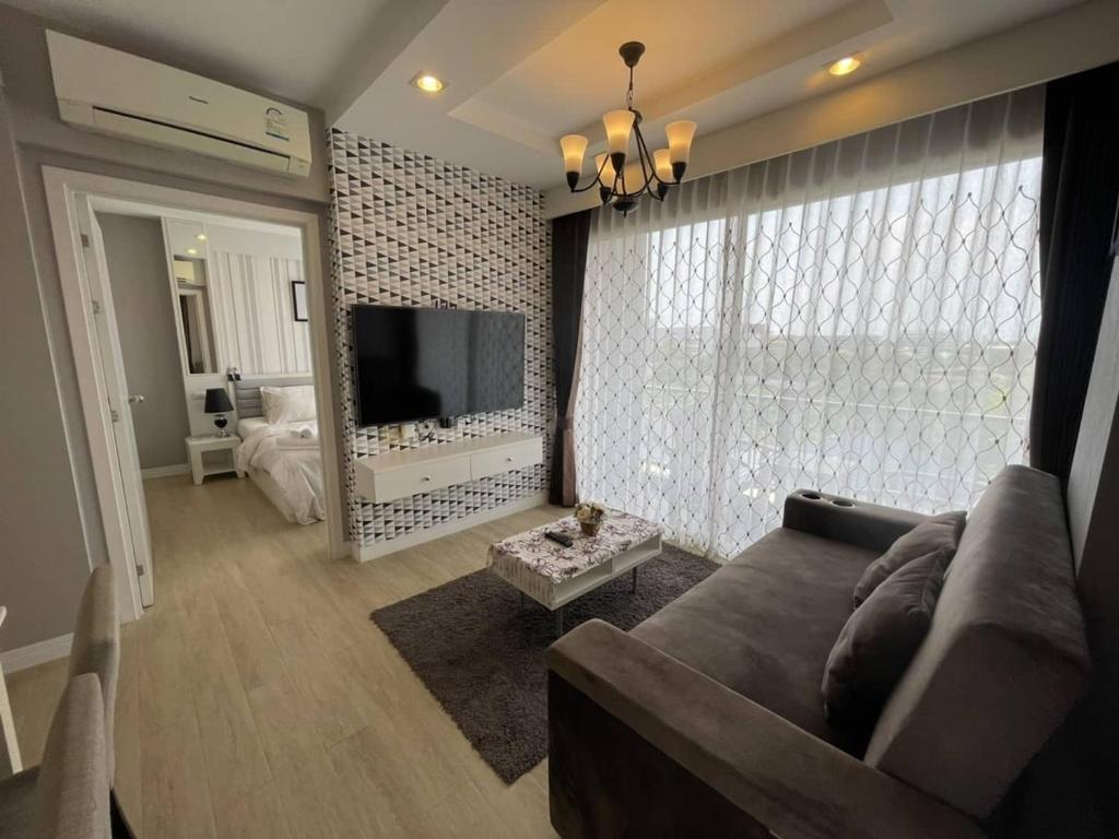 sala de estar con sofá y TV de pantalla plana en Execlusive Seaview 1 bedroom suite with toproof pool at The Patio Bangsaen en Bangsaen Sai 1