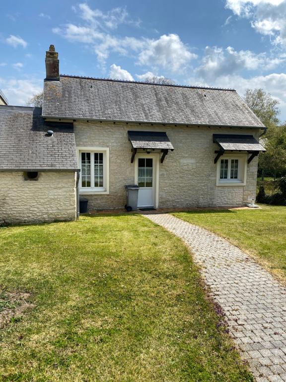 een oud stenen huis met een grindoprit bij Chez pépé in Arromanches-les-Bains