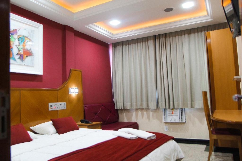 a hotel room with a bed and red walls at Capri Hotel in Duque de Caxias