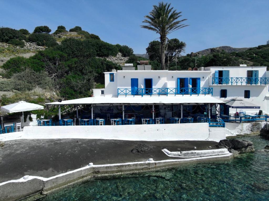 un edificio blanco con sillas azules en el agua en Agia Fotia Taverna, en Kerames
