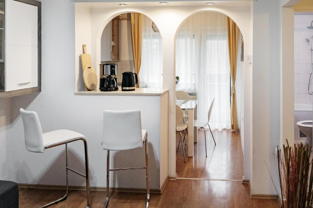 uma sala de estar com cadeiras brancas e uma cozinha em Apartments Šentvid em Liubliana