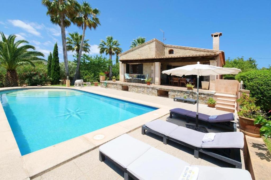 einen Pool mit zwei Liegestühlen und ein Haus in der Unterkunft Sa Vinyeta de Son Jaumell in Capdepera