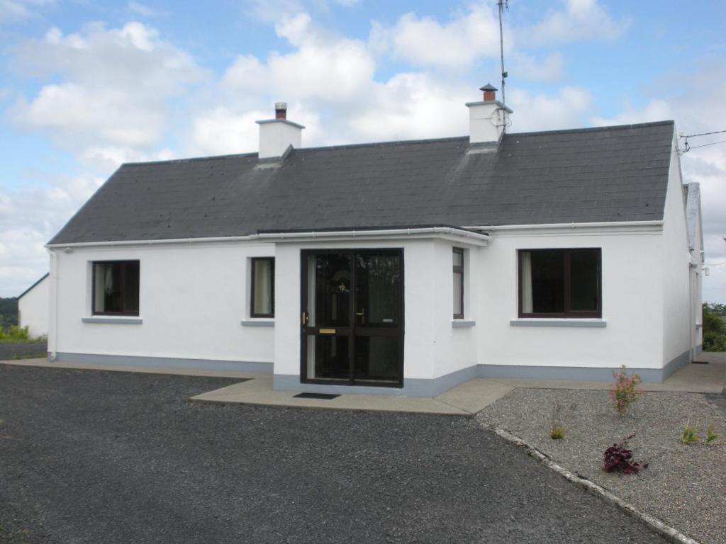 une maison blanche avec un toit noir dans l'établissement Beautiful 3-Bed House in Knock, à Knock