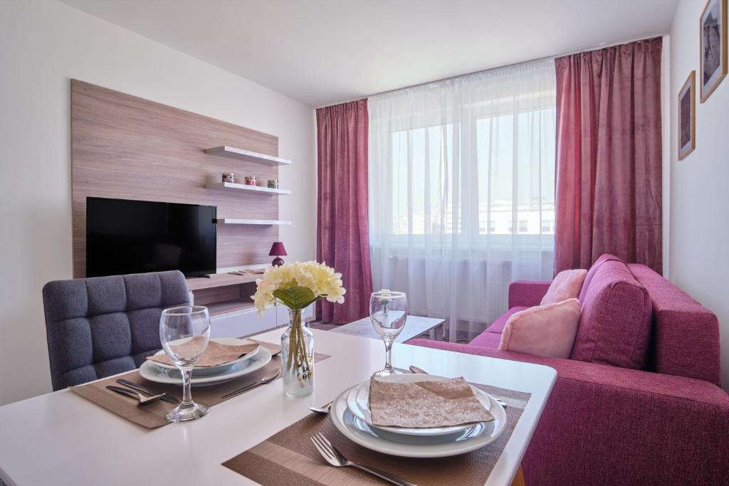 uma sala de estar com uma mesa e cadeiras roxas em 111Apartments em Košice