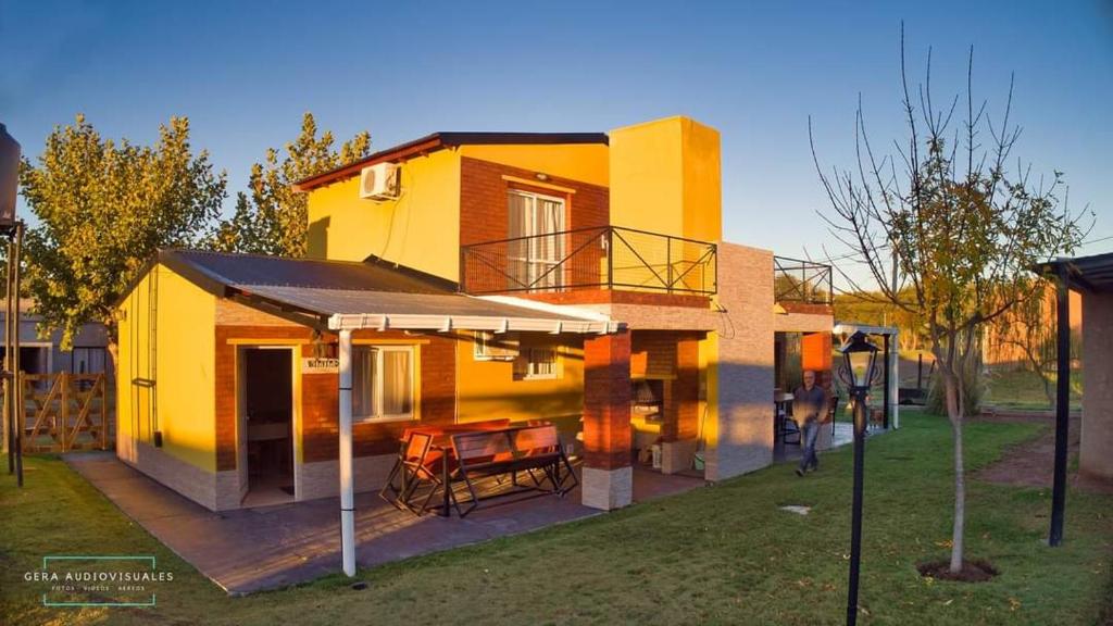 ein gelbes Haus mit einem Tisch und einer Terrasse in der Unterkunft Cabañas bajos medanales in Victorica