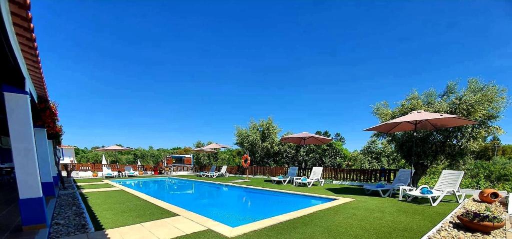 a swimming pool with chairs and umbrellas in a yard at Monte Família Ferreira in Vale de Açor