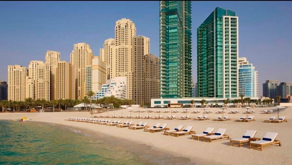 a beach with chaise lounges and chairs and buildings at Stunning 5* 4BR-Oceanfront-Apartment in Dubai