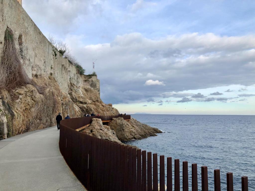 a person walking along a wall next to the ocean at U riposu in Bastia