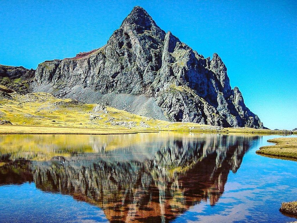 a mountain with its reflection in a body of water at Apartamentos Formigal - admite mascotas in Formigal