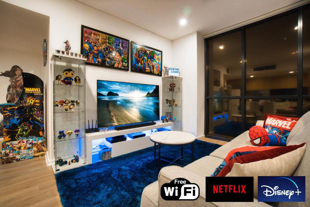 ein Wohnzimmer mit einem großen TV und einem Sofa in der Unterkunft DC vs Marvel Theme ft Arcade Machine Pool Gym Spa Sauna BBQ in Adelaide