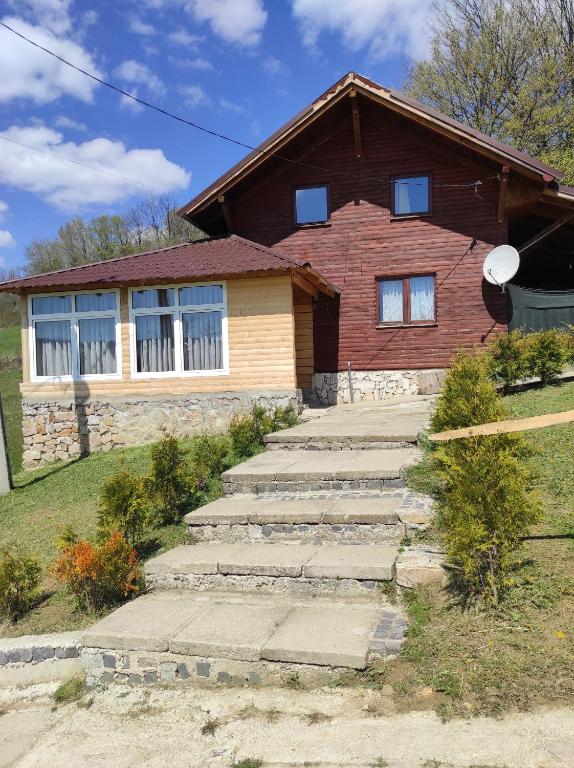 a house with a stone walkway in front of it at Cabana Roșia in Roşia