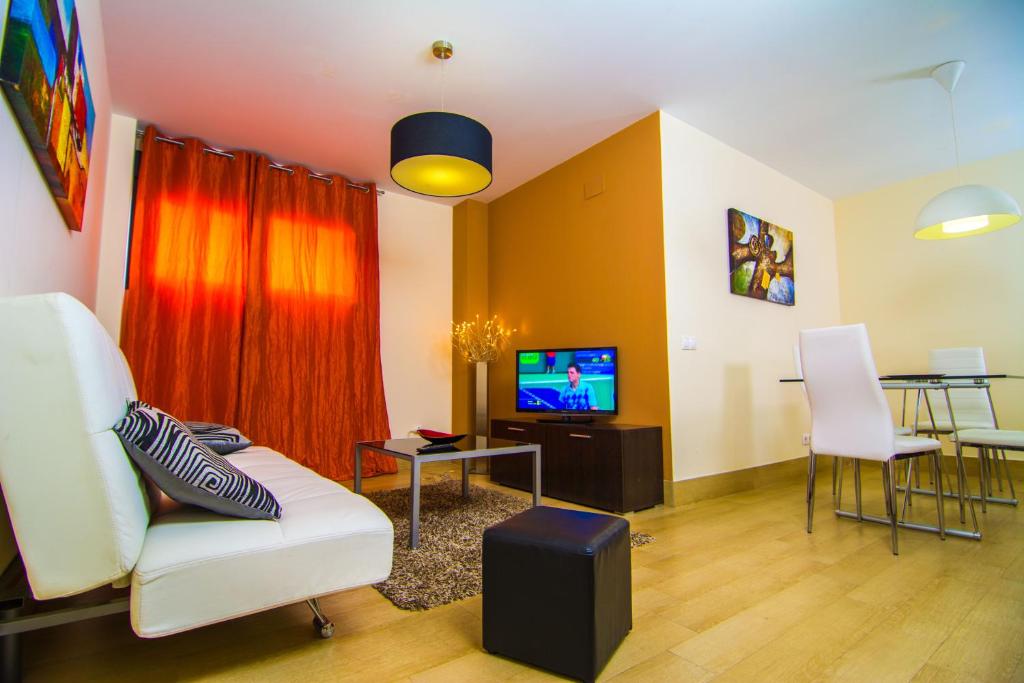 a living room with a white couch and a tv at Apartamentos 16:9 Playa Suites in Almería