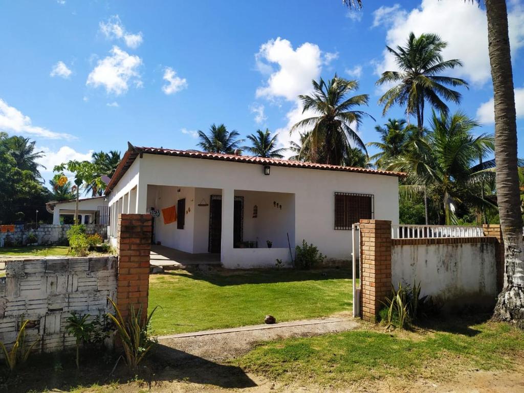 a white house with palm trees in the background at Doce Lar - Casa de Praia in Itapipoca