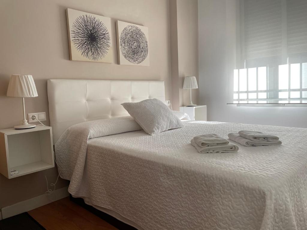 sypialnia z białym łóżkiem i 2 ręcznikami w obiekcie Apartamento La Mezquita-Catedral w Kordobie