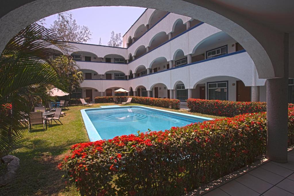 une cour avec une piscine dans un bâtiment fleuri dans l'établissement Hotel Arcos Aeropuerto, à Veracruz