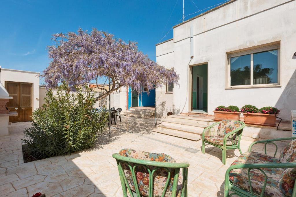 un patio avec des chaises et un arbre avec des fleurs violettes dans l'établissement Villetta Il Glicine by BarbarHouse, à Porto Cesareo