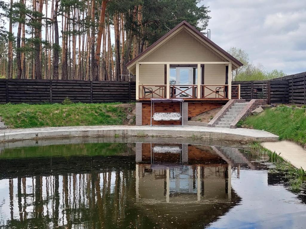 ein kleines Haus neben einem Wasserkörper in der Unterkunft Комплекс На Дачі in Vyshpolʼ