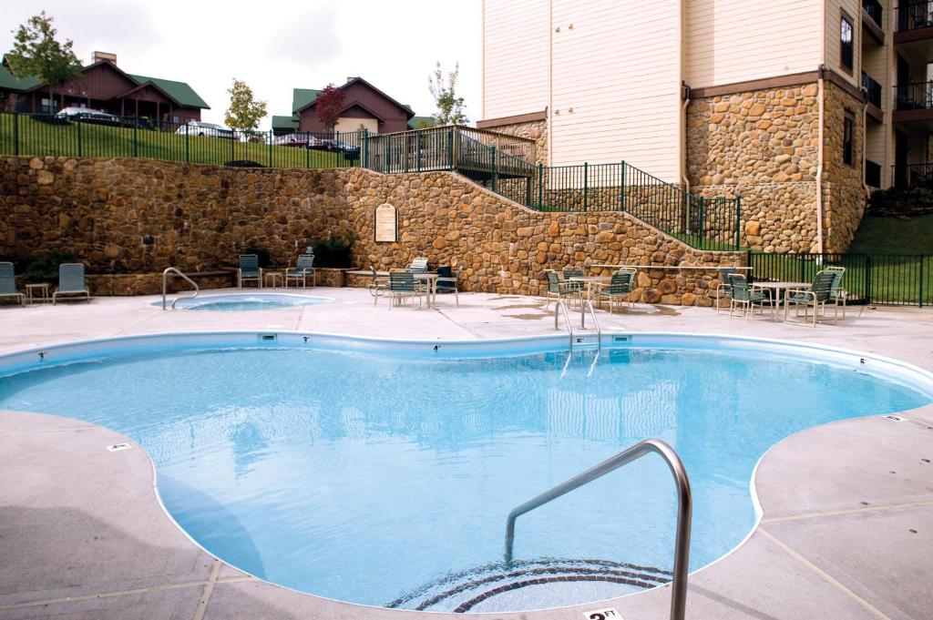 a large swimming pool in a hotel with tables and chairs at Club Wyndham Smoky Mountains in Pigeon Forge