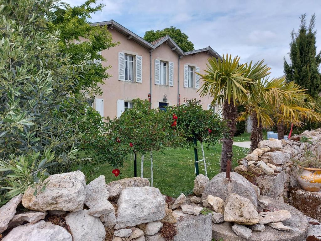 uma casa atrás de uma parede de pedra em frente a uma casa em Chateau Gunes (Guges) em Cissac-Médoc