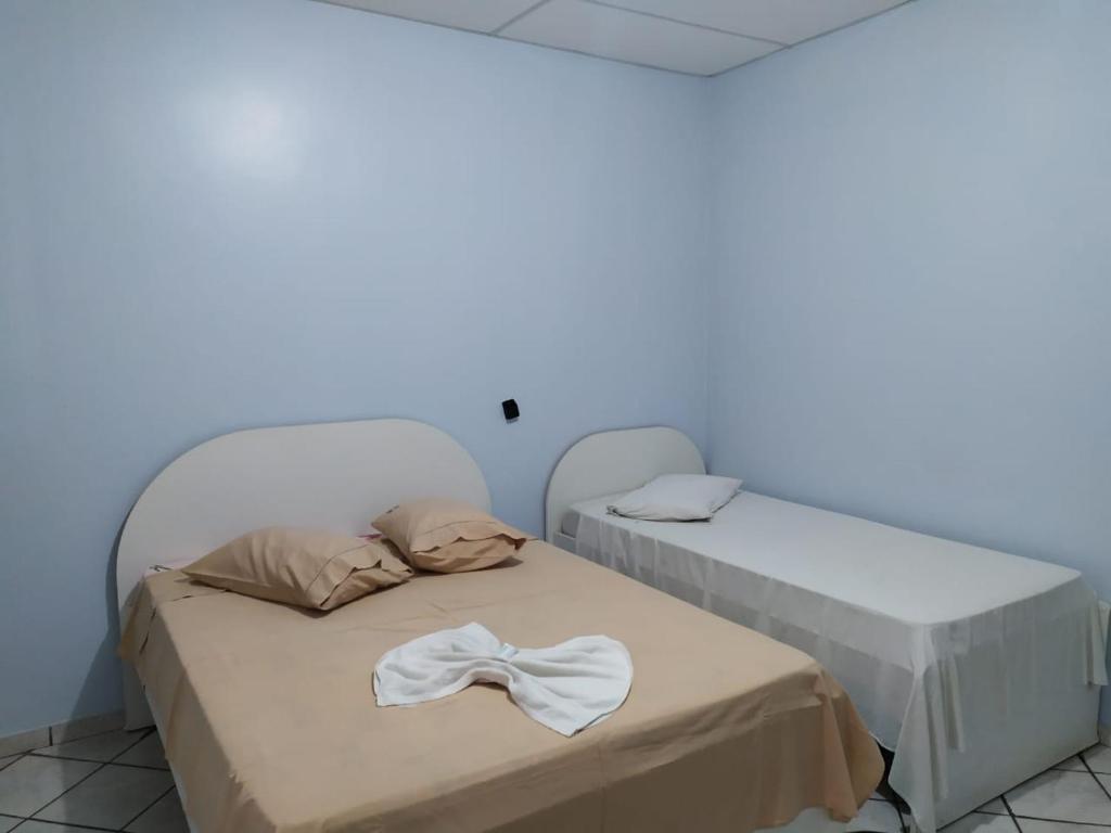 two beds in a room with a white wall at HOTEL GARCIA in Várzea Grande