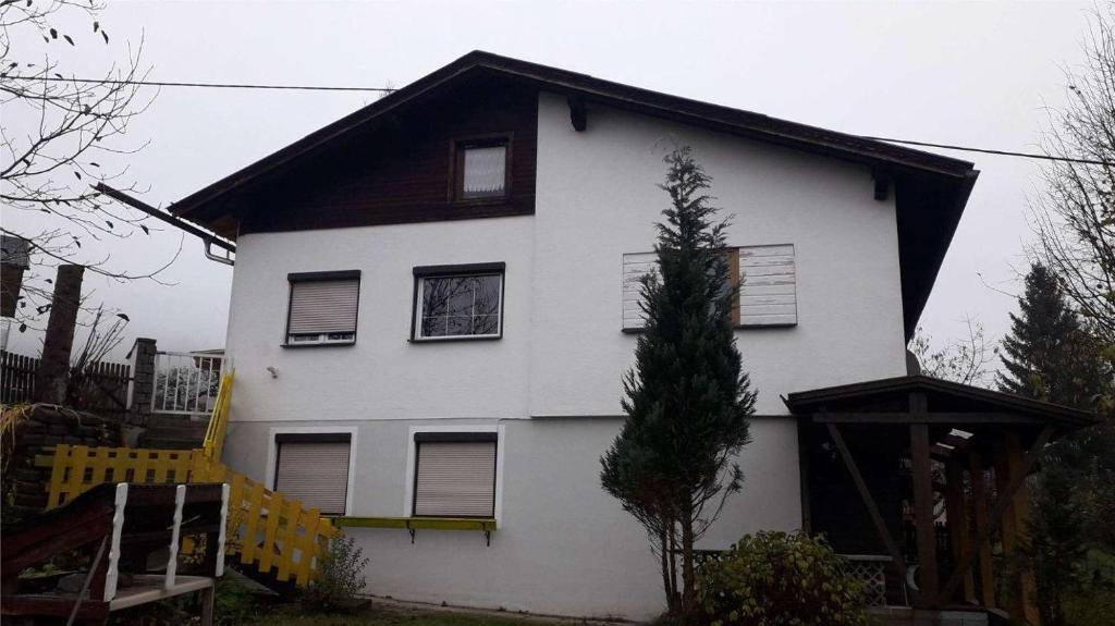 ein weißes Haus mit einem Baum davor in der Unterkunft Emi in Klagenfurt am Wörthersee