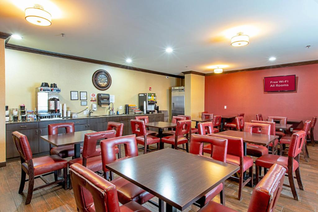 a restaurant with wooden tables and red chairs at Red Roof Inn & Suites Omaha - Council Bluffs in Council Bluffs